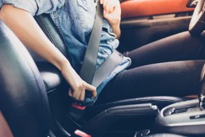 Woman fastening seat belt in the car.